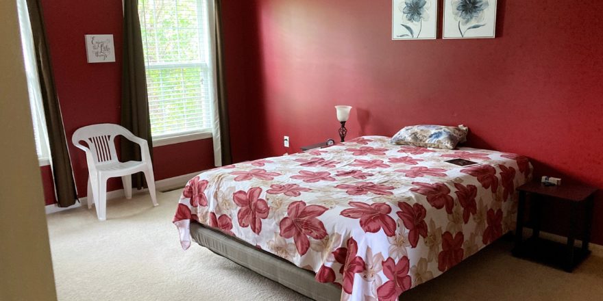 Carpeted bedroom with large bed, side tables and chair