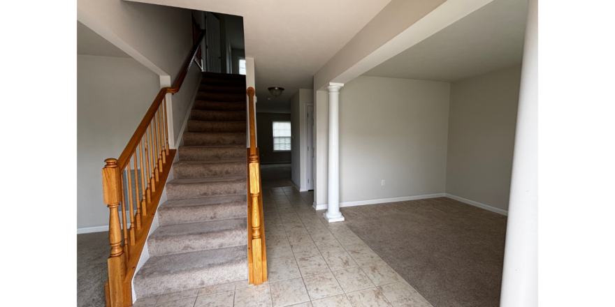 a large empty room with a staircase leading up to the second floor