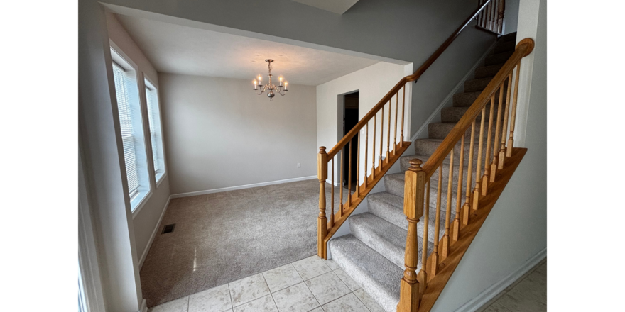 an empty room with a staircase and a chandelier