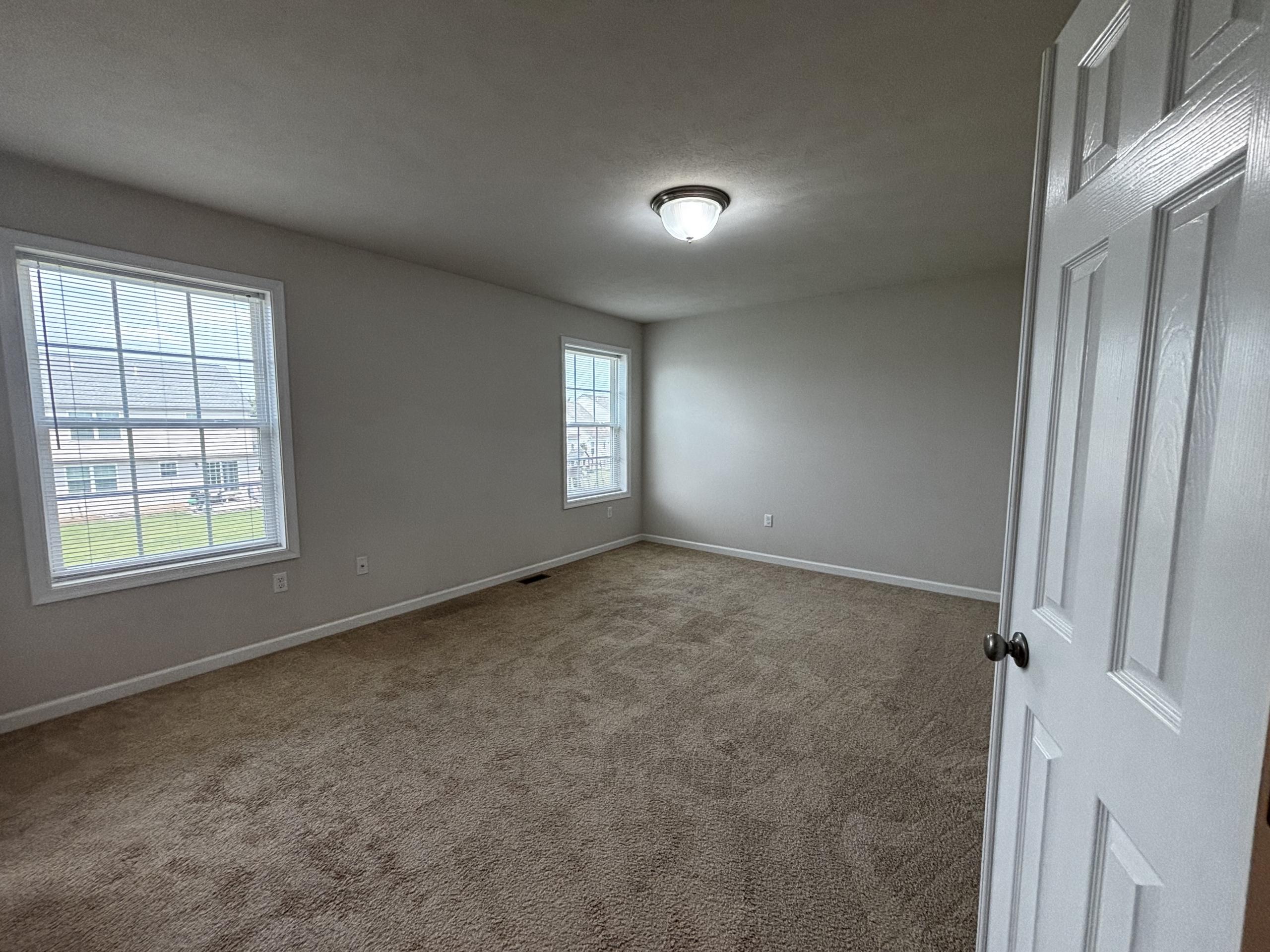 Empty bedroom with two windows and carpet