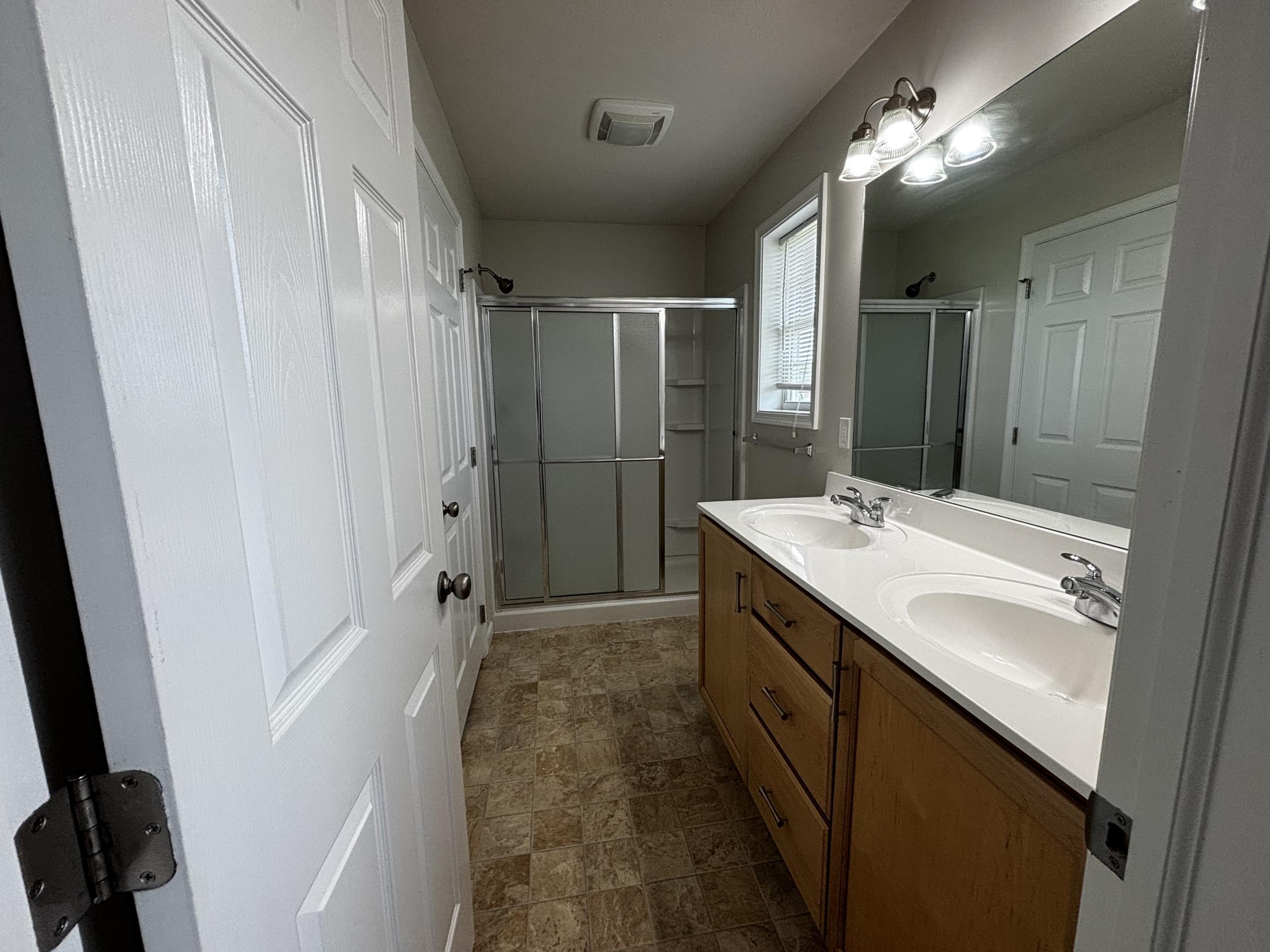 Bathroom with double vanity and shower