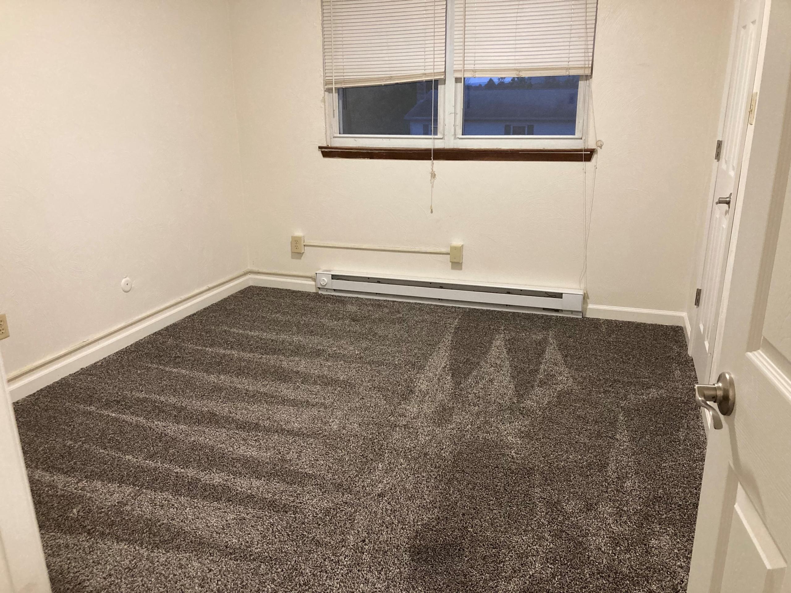 Empty room with carpeted floor and window blinds