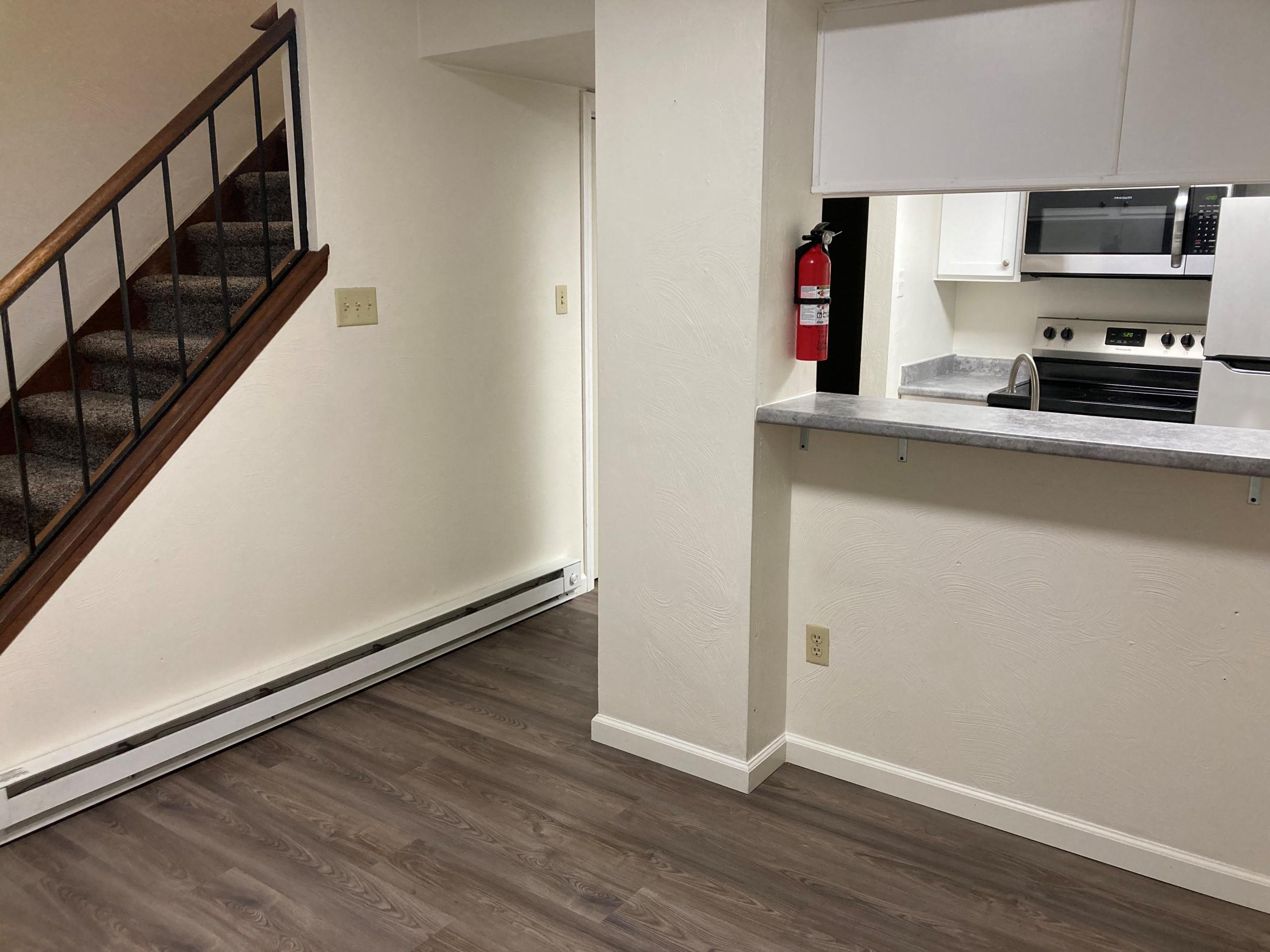 Empty apartment with hardwood floors, kitchen, and staircase