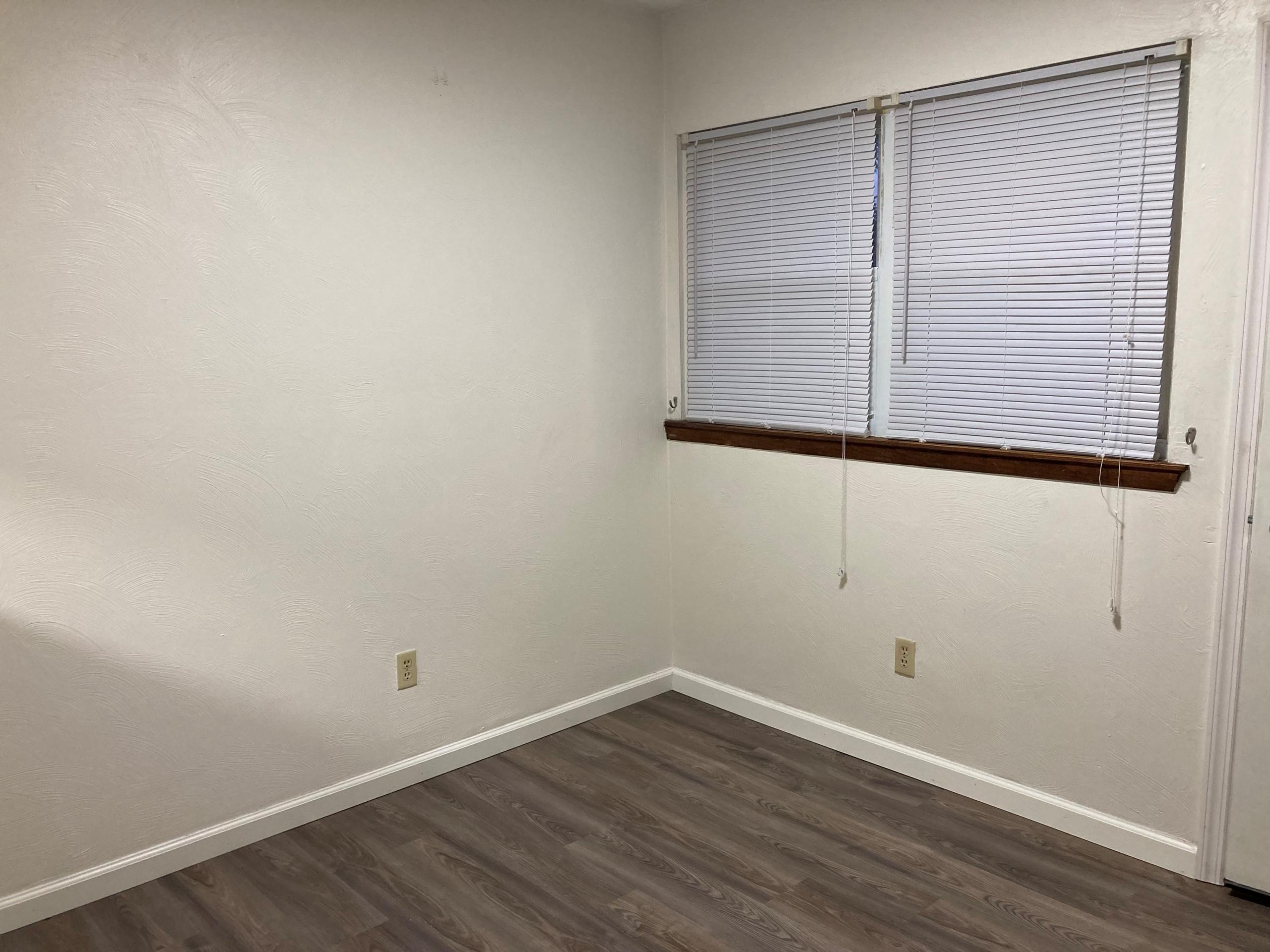 Empty room with white walls and wood floor, window with blinds