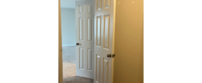 an empty room with a white door and carpet