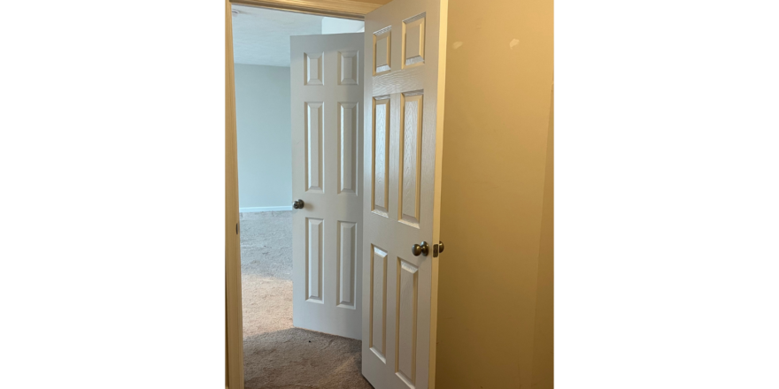 an empty room with a white door and carpet
