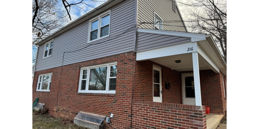 a brick house with white trim and a metal roof
