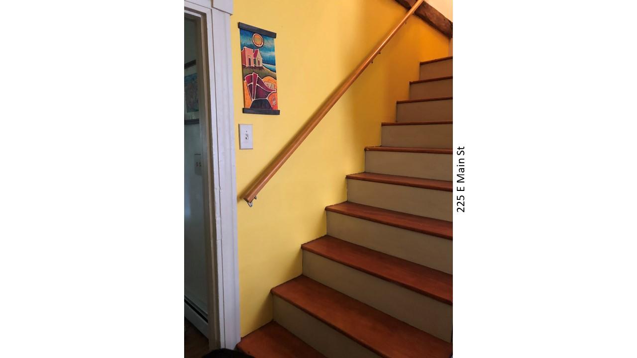 Staircase with yellow wall and art
