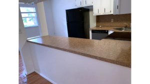 U-Shaped kitchen with white cabinets and stainless steel appliances and black fridge