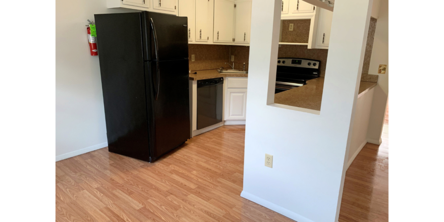 U-Shaped kitchen with white cabinets and stainless steel appliances and black fridge