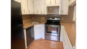 U-Shaped kitchen with white cabinets and stainless steel appliances and black fridge