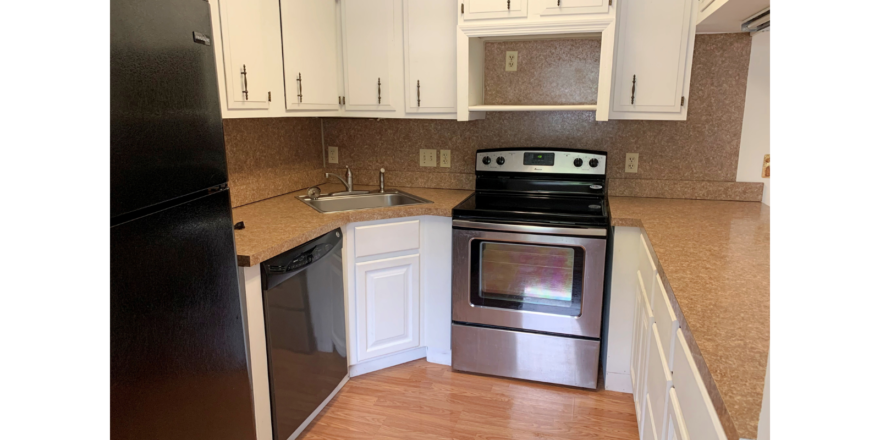 U-Shaped kitchen with white cabinets and stainless steel appliances and black fridge