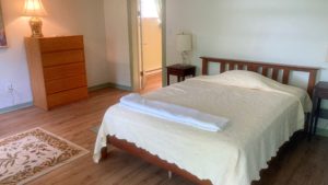 Bedroom with full bed, two end tables with lamps and a dresser with a lamp