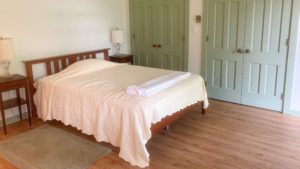 Bedroom with full bed, two end tables with lamps and two closets