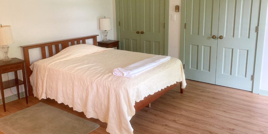 Bedroom with full bed, two end tables with lamps and two closets