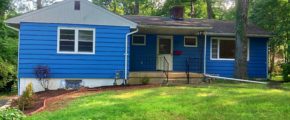 Exterior of ranch house with bright blue siding and front yard.