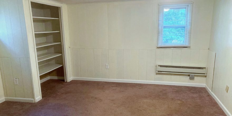 Unfurnished, carpeted bedroom with built in shelving