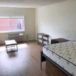 Living/sleeping area with desk, dining table, couch, and full-size bed