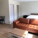 Living/sleeping area with desk, dining table, couch, and full-size bed