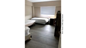 Bedroom with three beds, a dresser, and a desk