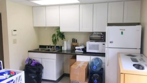 Kitchenette with appliances, cabinets, and sink