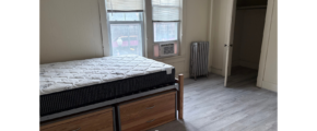 a bedroom with a bed, dresser, and window