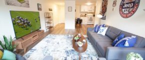 Living room with couch, chairs, large TV, and area rug