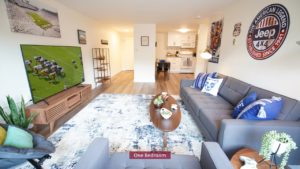 Living room with couch, chairs, large TV, and area rug