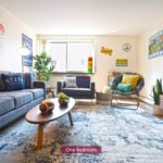 Living room with couch, chairs, large TV, and area rug