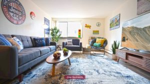 Living room with couch, chairs, large TV, and area rug