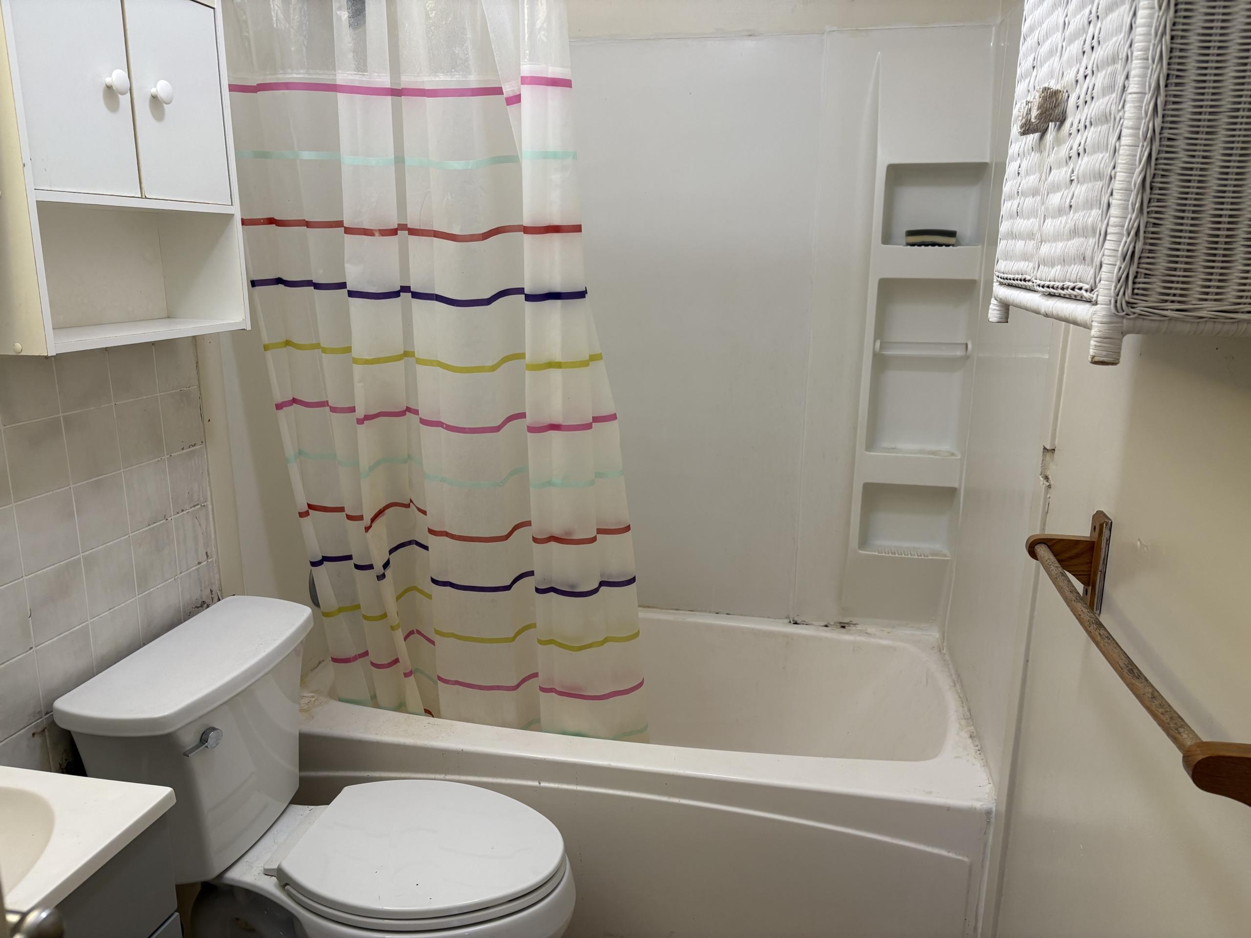 Bathroom with bathtub, toilet, and shower curtain