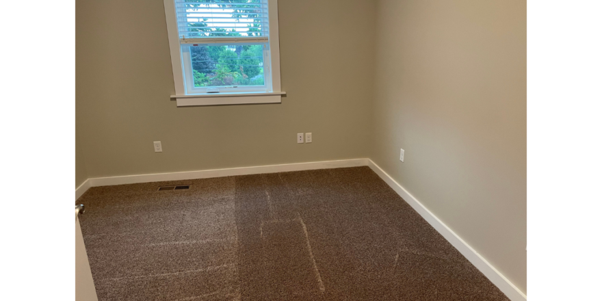 a empty room with a window and carpet