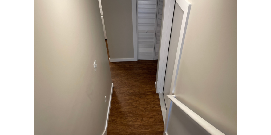 a narrow hallway leading to a door and a closet