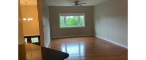 an empty living room with a ceiling fan