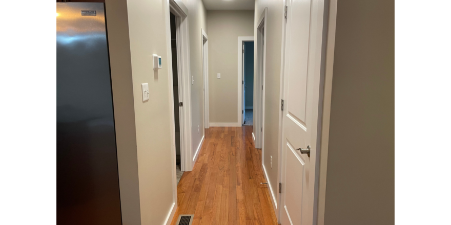 a long narrow hallway with wood floors and white walls