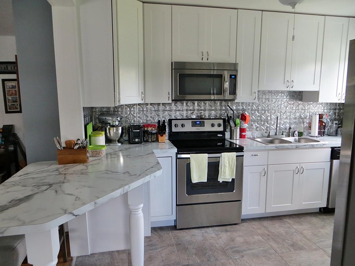 Modern white kitchen with stainless steel appliances.