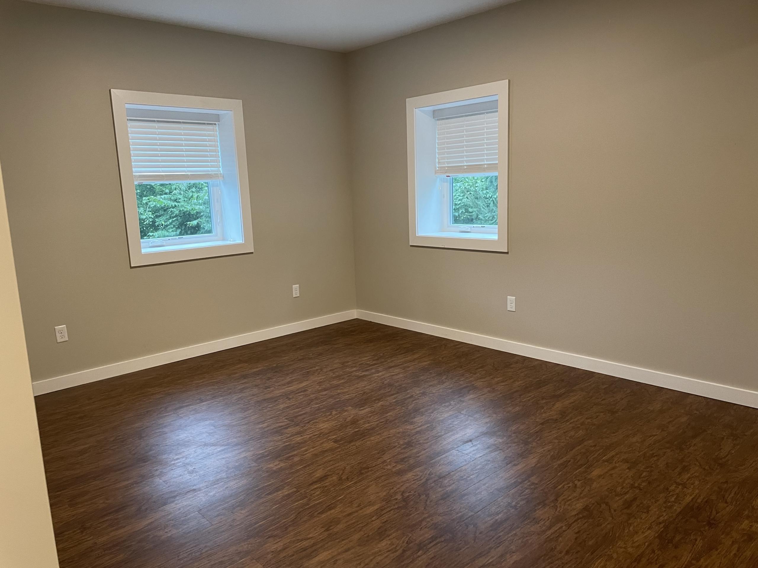Empty room with two windows and wood floor