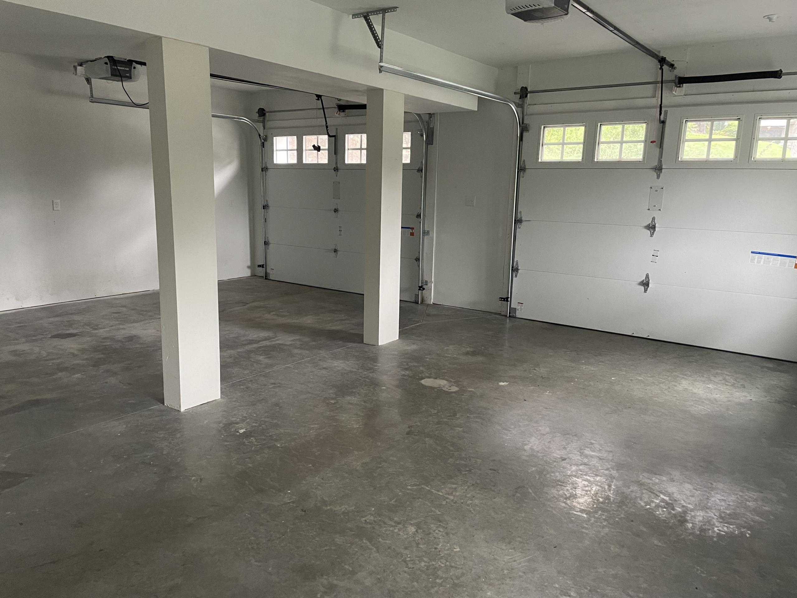 Empty garage with two white doors and concrete floor.