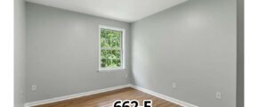 an empty room with a window and hard wood floor