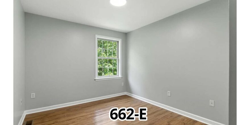 an empty room with a window and hard wood floor