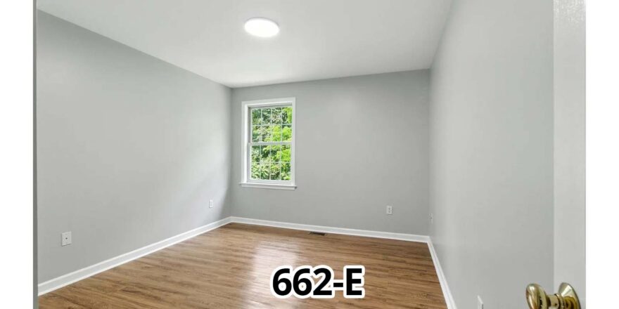 an empty room with wood floors and a window
