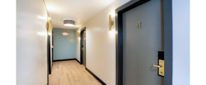 a long hallway with a blue door and white walls