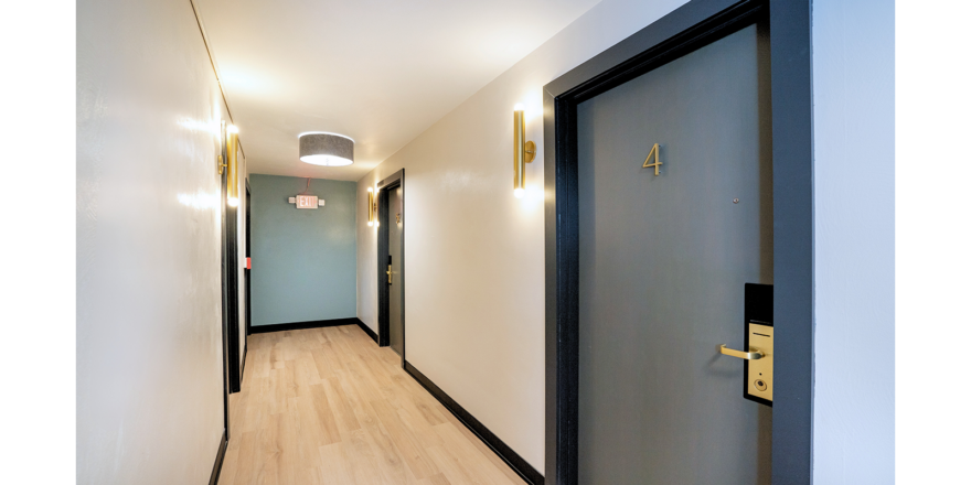 a long hallway with a blue door and white walls