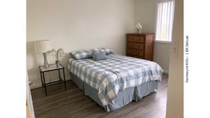 Bedroom with full-size bed, end table, and dresser