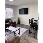 Living room with arm chair, barstools, potted plant, tv, and decor
