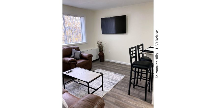 Living room with arm chair, barstools, potted plant, tv, and decor