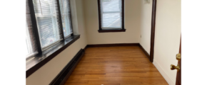 an empty room with wood floors and windows