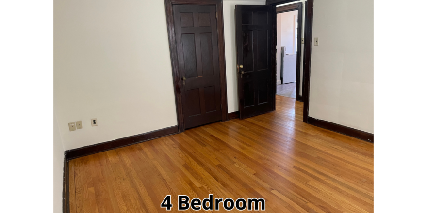 an empty room with wooden floors and black doors