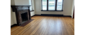 an empty living room with a fireplace and hard wood floors
