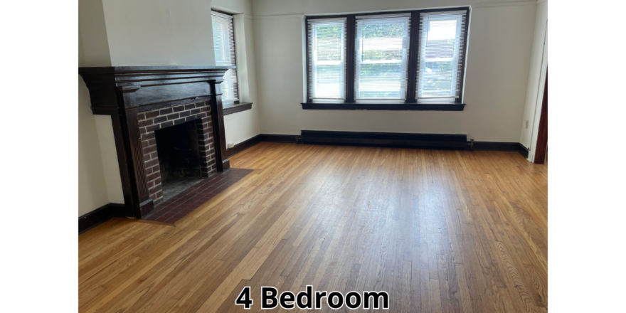 an empty living room with a fireplace and hard wood floors